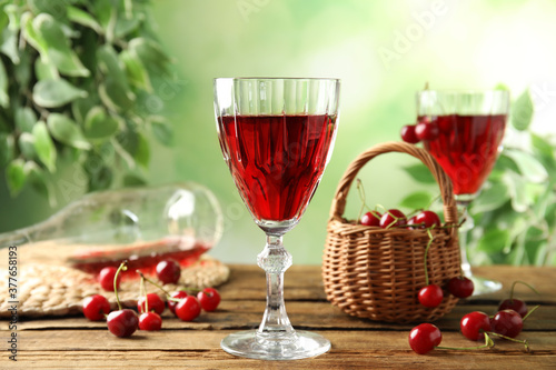 Delicious cherry wine with ripe juicy berries on wooden table