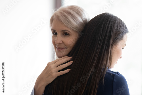 Caucasian middle-aged 50s woman mother embrace lean comfort adult millennial daughter showing love and care. Senior 60s mom and grownup girl child hug reconcile after fight. Support, family concept.