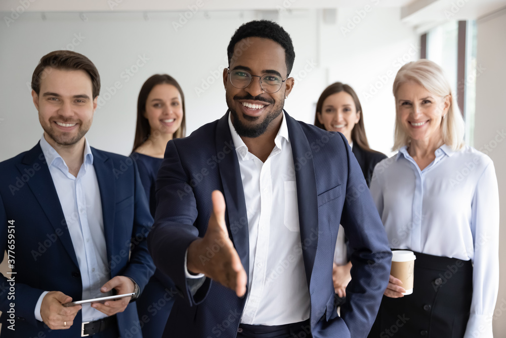 Portrait of smiling African American team leader stretch hand greeting job candidate or applicant in office. Happy multiracial businesspeople meet welcome newcomer at workplace. Employment concept. - obrazy, fototapety, plakaty 
