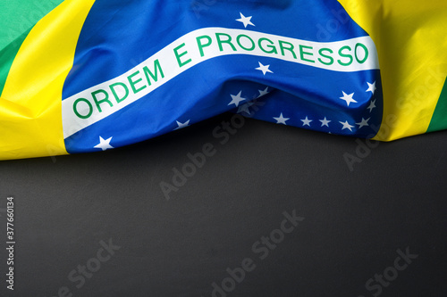 Brazilian flag lying on black grainy background photo