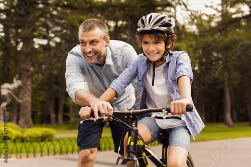 Boy learning how to ride bicycle with his happy dad