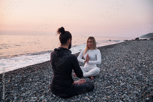 a guy and a girl are sitting on the beach in the lotus position namaste hands