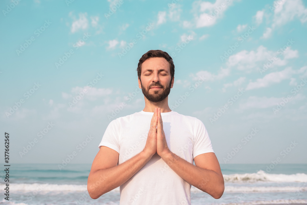 happy guy sits on the seashore and meditates.