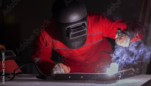 Young repairman with a welding gun electrode and a helmet weldin