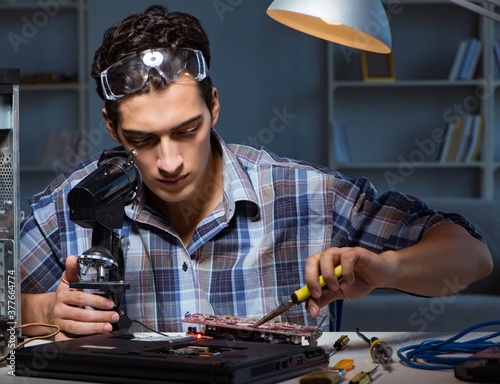 Repairman trying to repair laptop with miscroscope photo