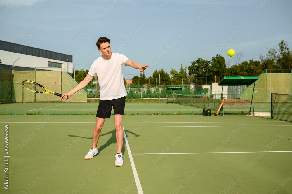 Male tennis player with racket hits the ball