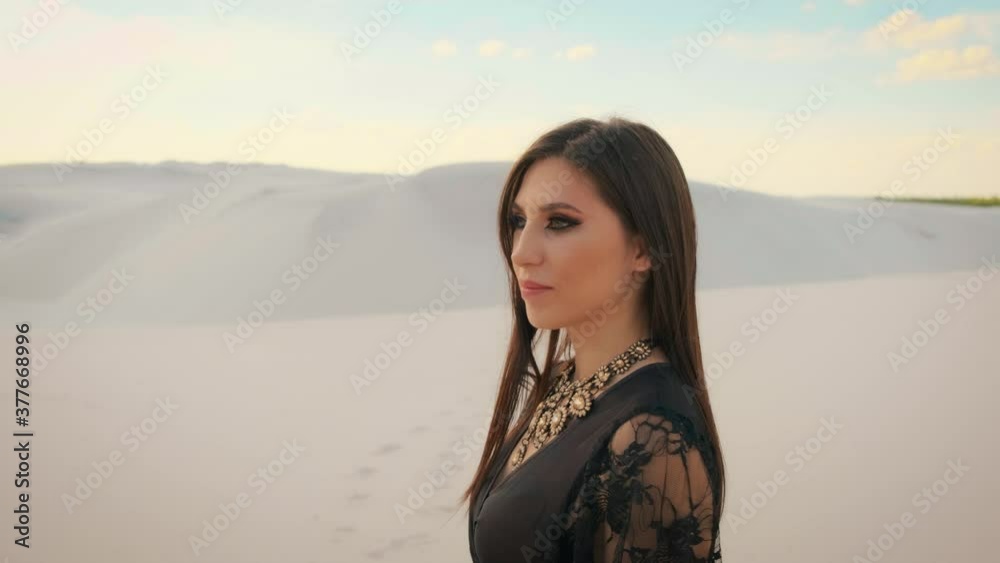 Portrait of a young attractive brunette woman with long hair. Beautiful makeup in oriental style smokey eyes. pretty face. Desert background with white sand dunes. Portrait of a young attractive brunette woman with long hair. Beautiful makeup in oriental style smokey eyes. pretty face. Desert background with white sand dunes.