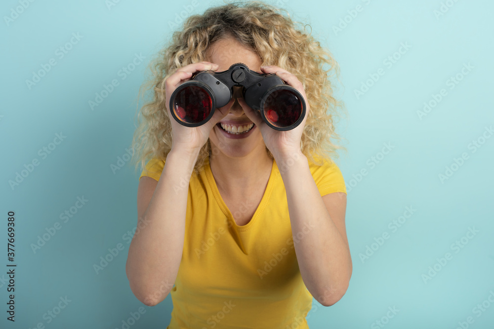 Happy girl looks with binocular something. Cyan background Happy girl looks with binocular something. Cyan background