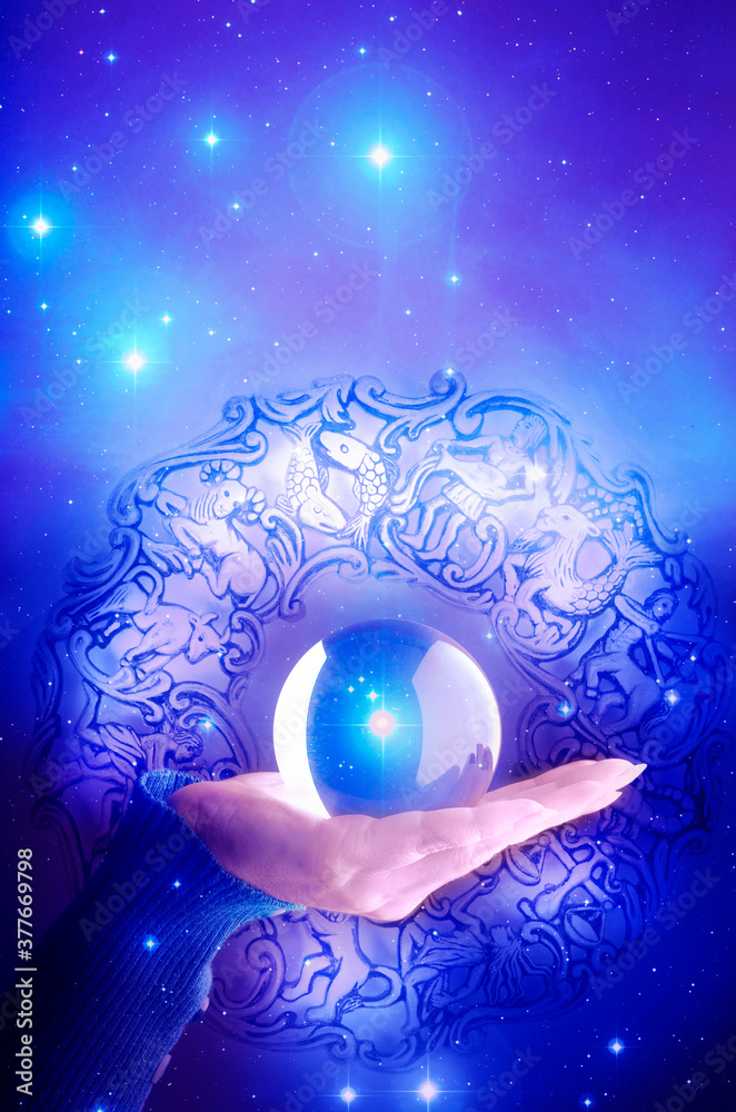 Fototapeta premium woman hand with crystal ball over blue background with stars, horoscope and zodiac and copy space like astrology concept