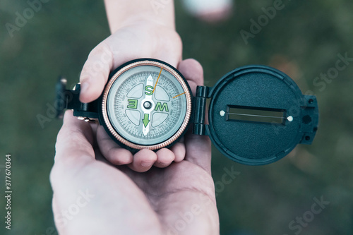 Father and daughter hands holding compass on green grass background.