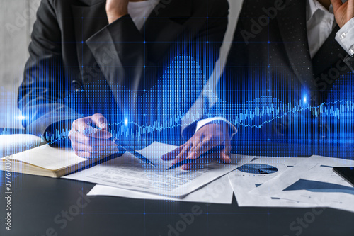 Two businesswomen working together in office. Forex graph holographic illustration double exposure.