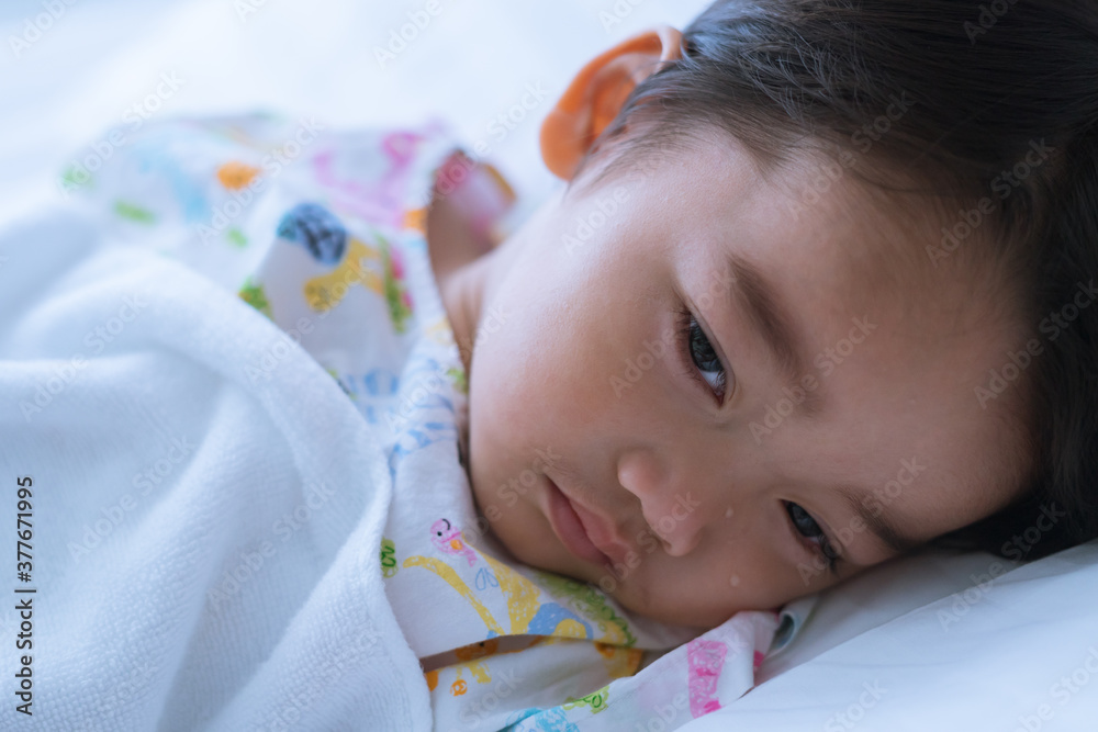 Asian cute little boy is lying sadly on the sickbed and the face with tears in the patient room in hospital. Healthcare medical and people concept.