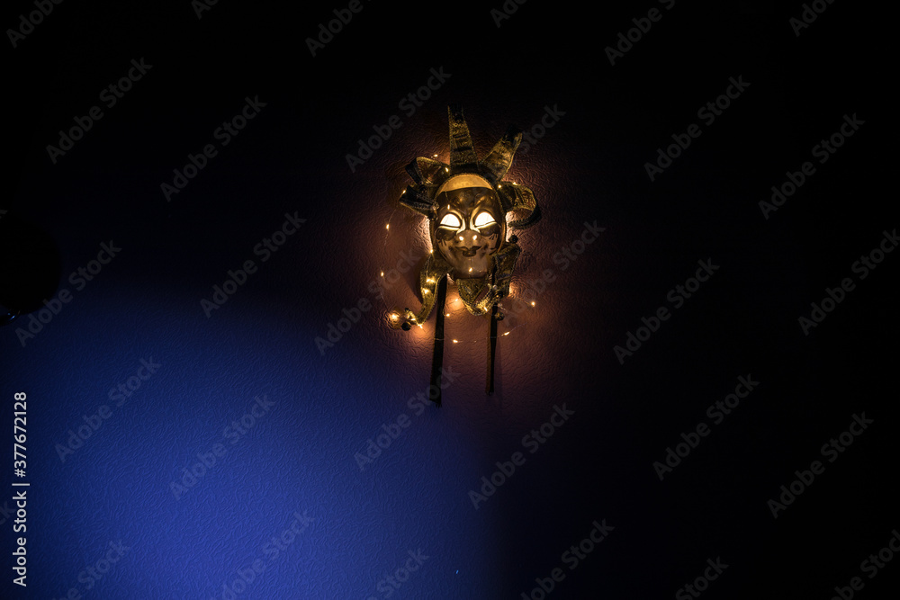 Horror concept. Scary mask with light on the wall inside dark room. Selective focus