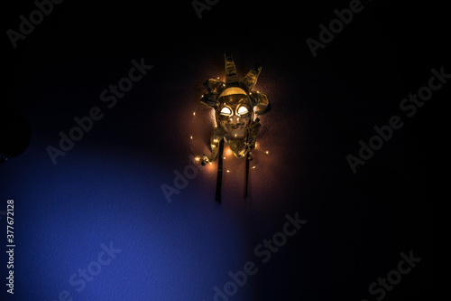 Horror concept. Scary mask with light on the wall inside dark room. Selective focus
