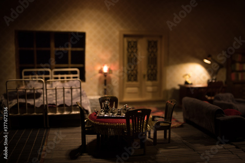 A realistic dollhouse living room with furniture and window at night. Artwork table decoration with handmade realistic dollhouse. Man wathing retro style Television in dark room. photo