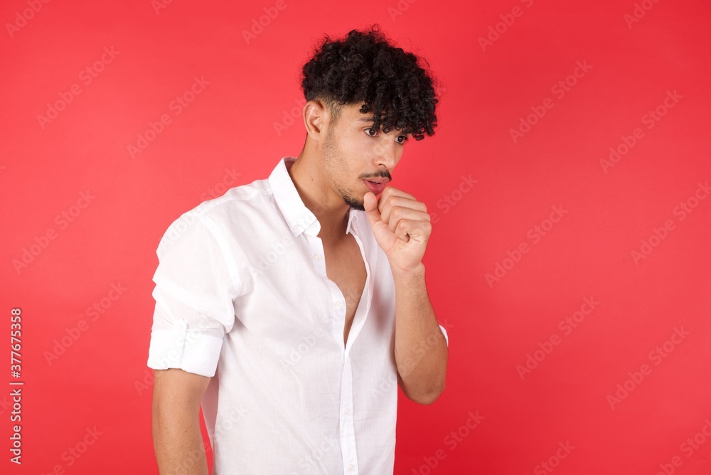 Young arab man with afro hair wearing shirt standing over isolated red background feeling unwell and coughing as symptom for cold or bronchitis. Healthcare concept. Young arab man with afro hair wearing shirt standing over isolated red background feeling unwell and coughing as symptom for cold or bronchitis. Healthcare concept.