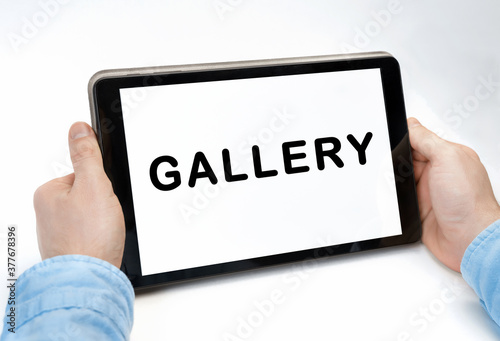 Male hands holding tablet pc with text GALLERY on white background