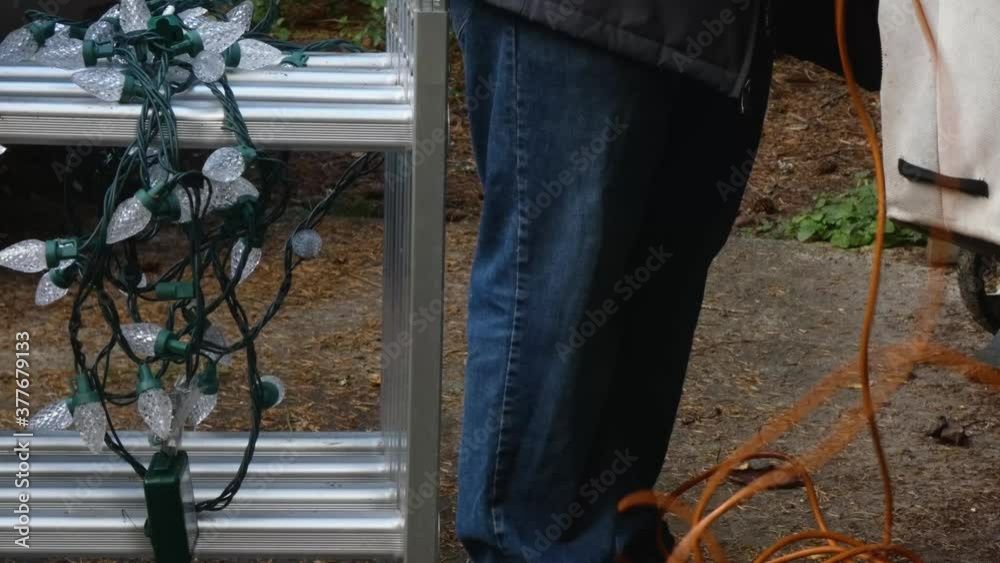 man using a ladder to set up christmas lights man using a ladder to set up christmas lights