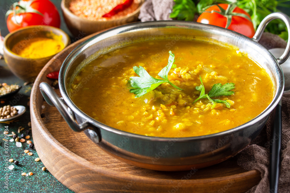 Indian cuisine. Traditional Indian spicy lentil puree soup with herbs on a dark background.