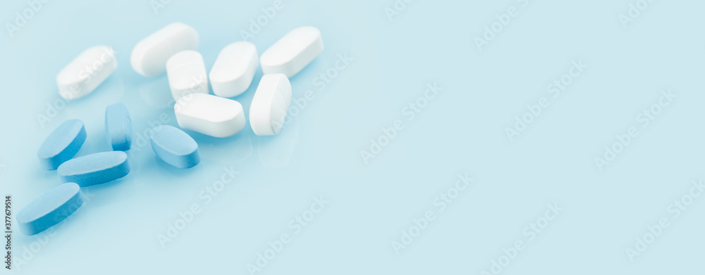 Medical banner of many white and blue capsule tablets or pills on the table. Close up edgeless. Healthcare pharmacy and medicine concept. Painkillers or prescription drugs consumption. copy space Medical banner of many white and blue capsule tablets or pills on the table. Close up edgeless. Healthcare pharmacy and medicine concept. Painkillers or prescription drugs consumption. copy space