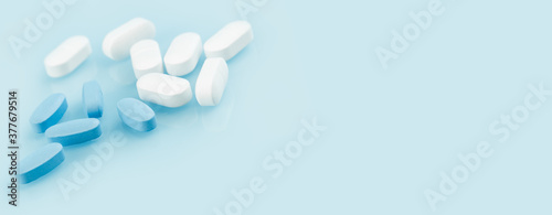 Medical banner of many white and blue capsule tablets or pills on the table. Close up edgeless. Healthcare pharmacy and medicine concept. Painkillers or prescription drugs consumption. copy space