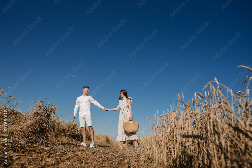 Young couple in the wheat field on sunny summer day. Couple in love have fun in golden field. Romantic couple in casual clothe outdoodrs on boundless field Young couple in the wheat field on sunny summer day. Couple in love have fun in golden field. Romantic couple in casual clothe outdoodrs on boundless field
