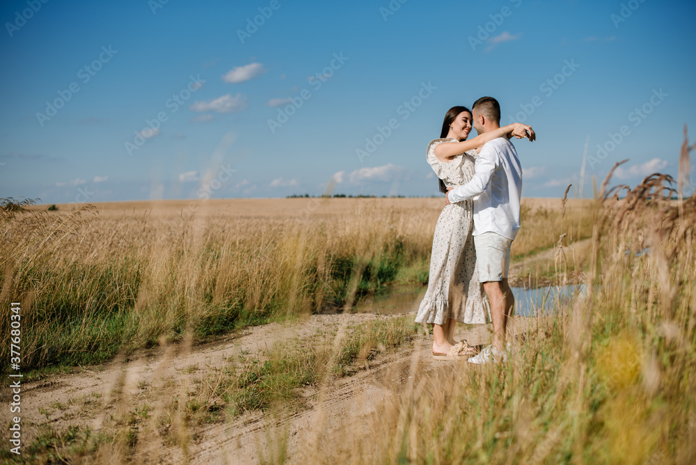 Young couple in the wheat field on sunny summer day. Couple in love have fun in golden field. Romantic couple in casual clothe outdoodrs on boundless field Young couple in the wheat field on sunny summer day. Couple in love have fun in golden field. Romantic couple in casual clothe outdoodrs on boundless field