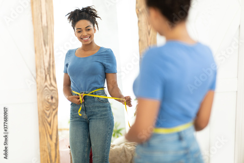 Happy Black Girl After Weight Loss Measuring Waist At Home photo