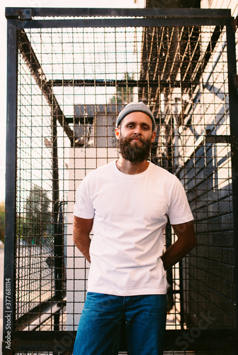 Young bearded hipster guy wearing white blank t-shirt. Mock-up for print. T-shirt template.