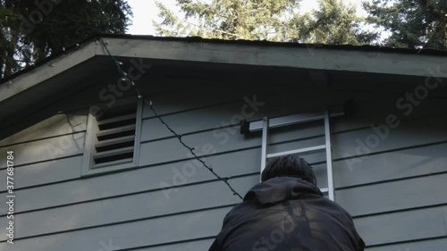 man using a ladder to set up christmas lights