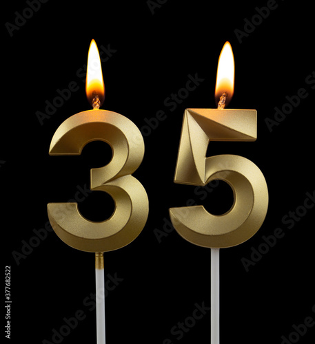 Burning golden birthday candles on black background, number 35 
