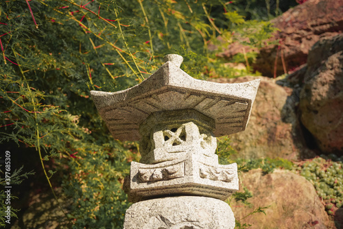 Chinesische Pagode aus Stein steht im Garten neben einem Ahornbusch