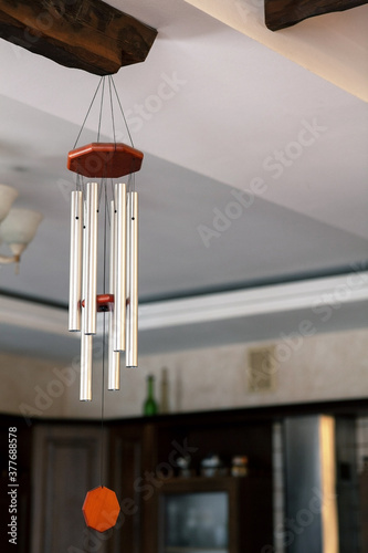 Traditional Chinese Feng shui interior object called chime tree or wind music, made from steel tubes. Relaxation, cleansing aura and defense from negative energy, hanging on the wooden bar on ceiling.