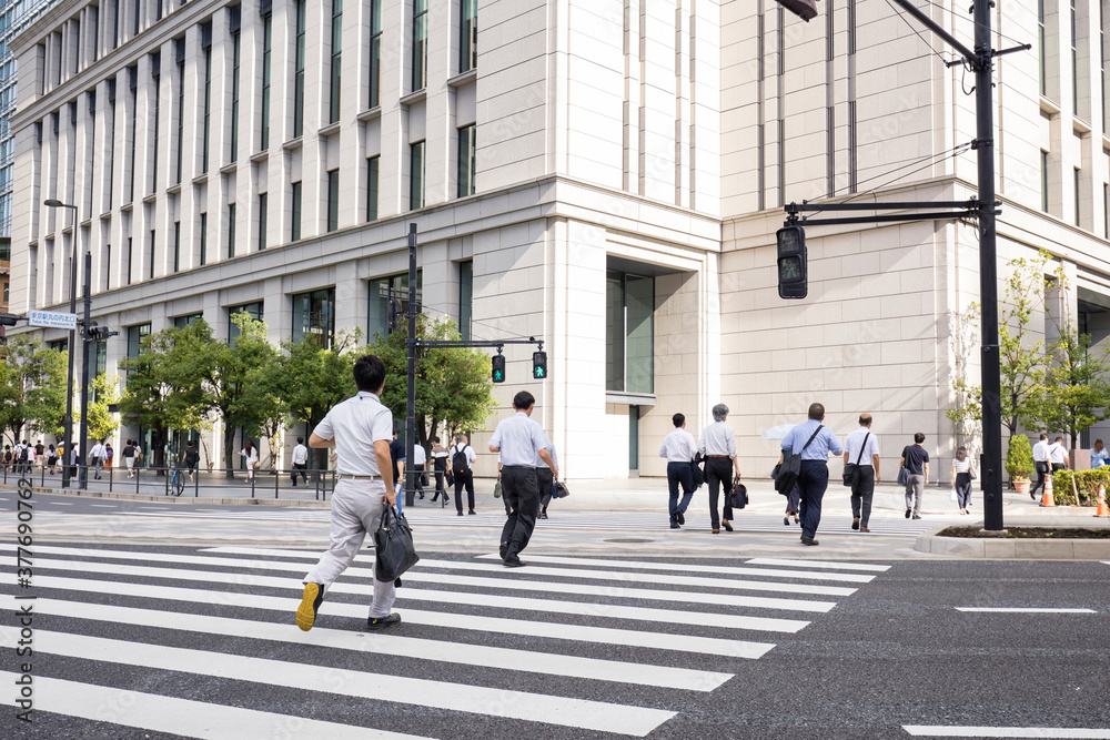 走って横断歩道を渡るビジネスマンの後ろ姿