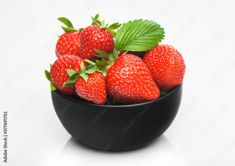 Fresh raw organic strawberries in black ceramic bowl plate on white background. Best summer berries. Fresh raw organic strawberries in black ceramic bowl plate on white background. Best summer berries.