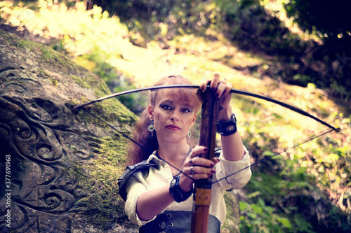 redhead girl in armor with a crossbow in the mountains
