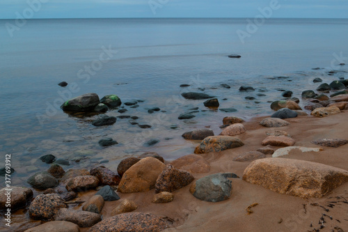 sandy pebble shore with stones and rocks of Ladoga blue lake in autumn