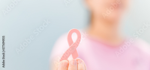 Woman wearing pink t shirt holding pink ribbon.Oncology.breast cancer awareness, October pink, World cancer day concept.banner background.Healthcare Tele medicine.Fight and Survivor with hope.