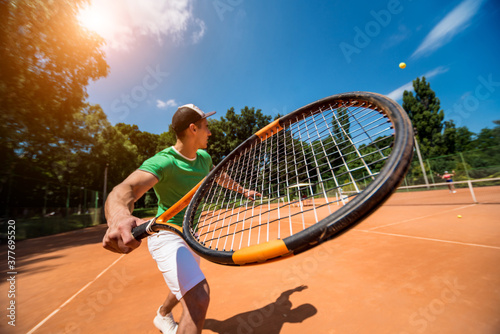 Young athletic man playing tennis on the court. © romaset