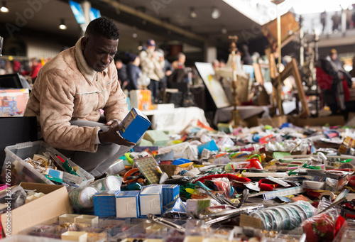 ordinary Afro-American guy considers things sacond hands on flea market