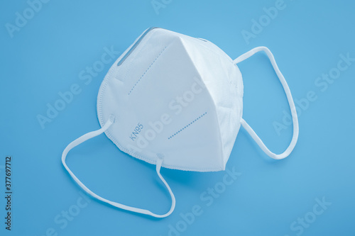 Surgical KN95 respirator, white protective medical face mask to cover the mouth and nose. Blue background. Covid-19 prevention, protection concept from сoronavirus disease pandemic.