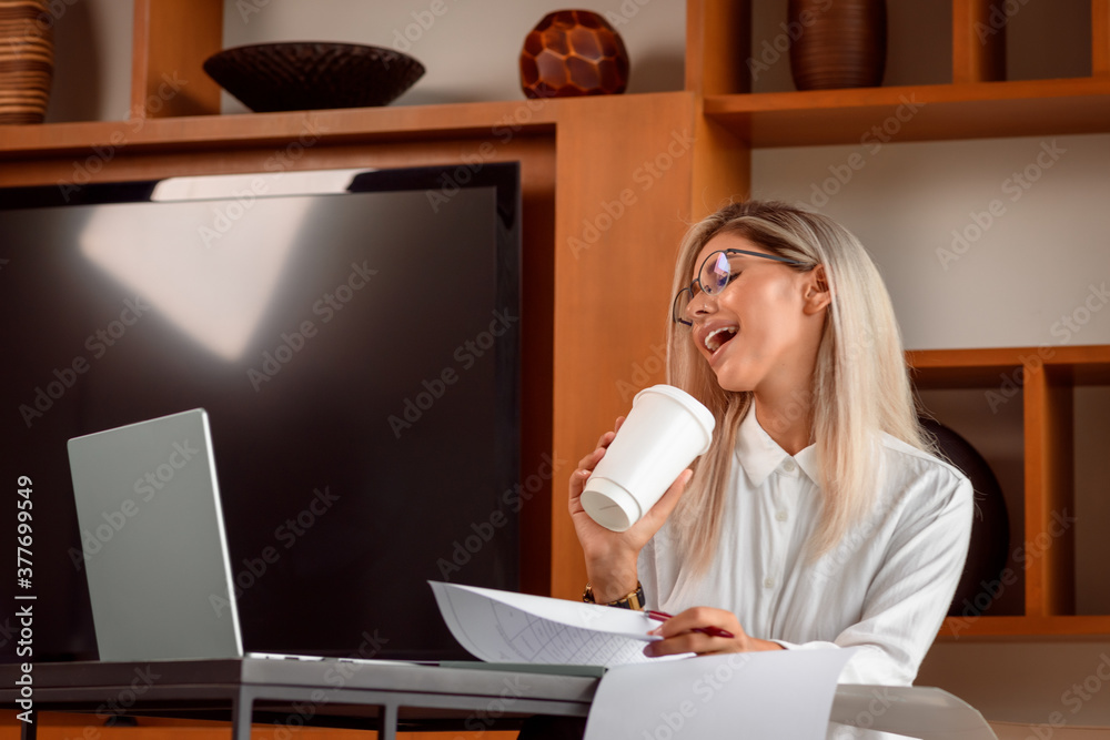 Photo of an excited young woman foolishly singing into a glass of coffee. Take a break from work for a laptop at home Photo of an excited young woman foolishly singing into a glass of coffee. Take a break from work for a laptop at home