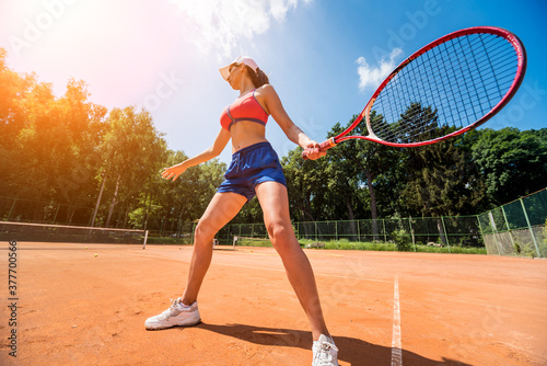 Young athletic woman playing tennis on the court.