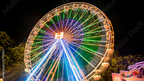 Ferries wheel rotating at night with lights at amusement park.