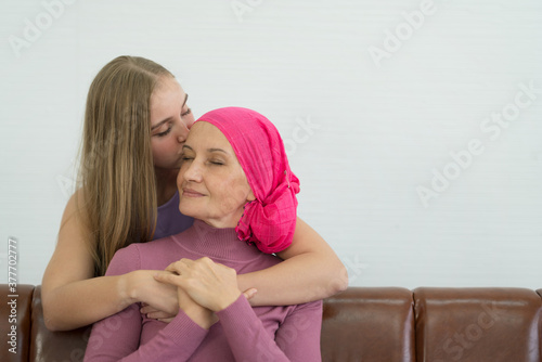 Young adult female cancer patient spending time with her daughter at home. Take medicine family support concept. photo