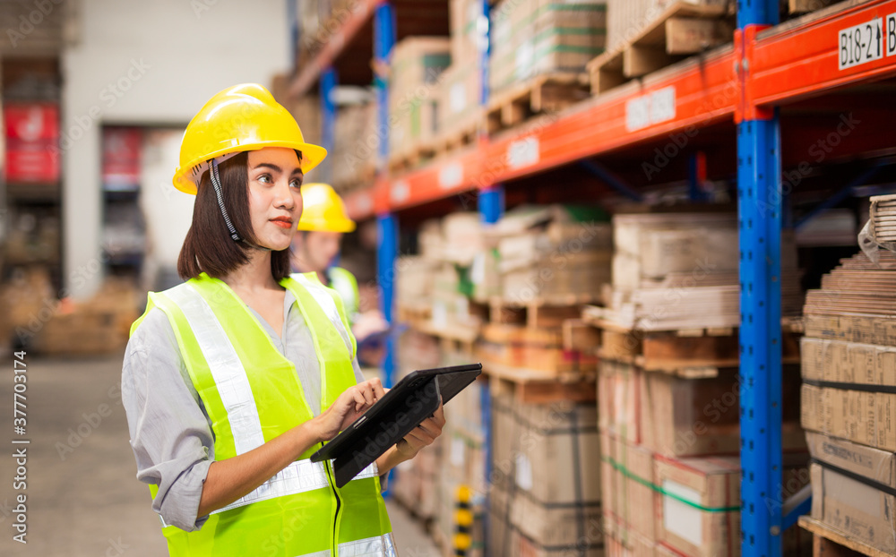 Young woman looking up order details on a tablet as he shops in a hardware warehouse for supplies , close up upper body Young woman looking up order details on a tablet as he shops in a hardware warehouse for supplies , close up upper body