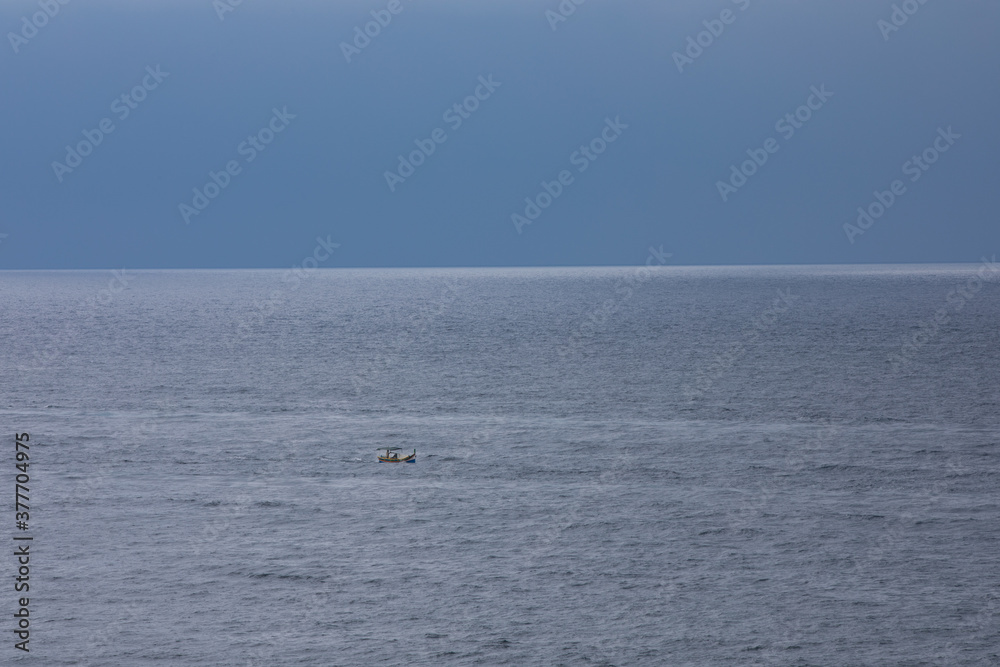 small boat at rough sea and windy weather, cloudy.