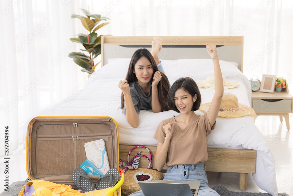 Two young asian women are using laptop to plan travel, book tickets, and booking accommodation online in bedroom. concept of travel in summer and holiday. Two young asian women are using laptop to plan travel, book tickets, and booking accommodation online in bedroom. concept of travel in summer and holiday.