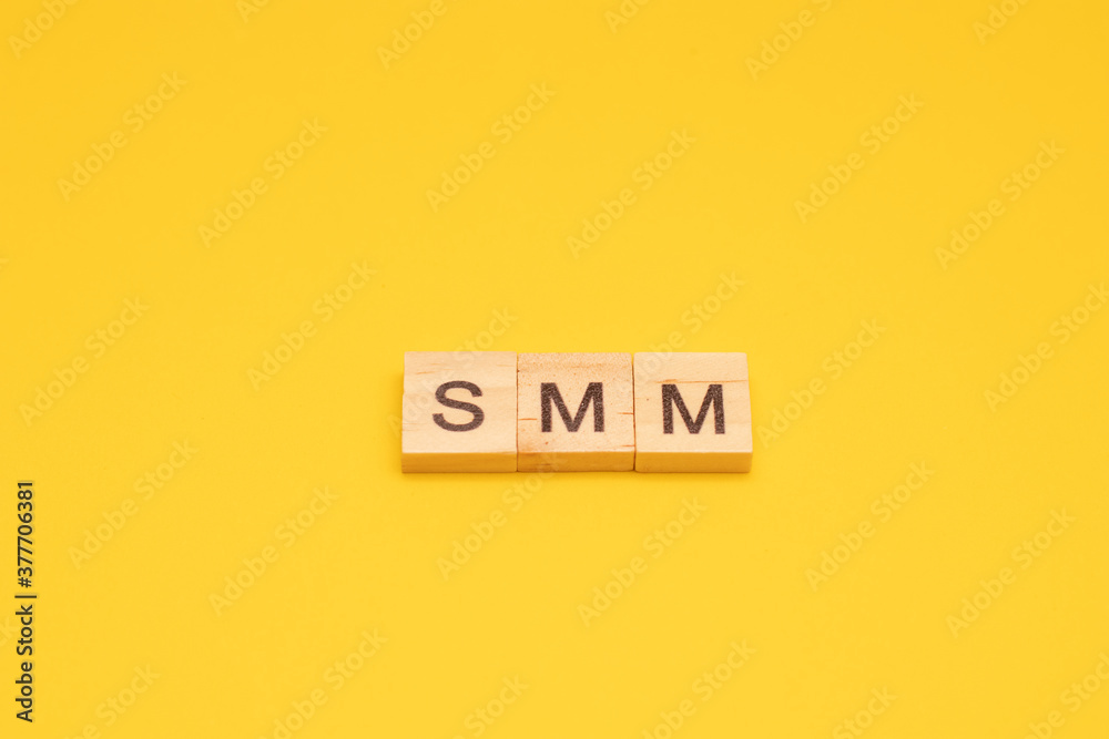 The word SMM made from wooden cubes on a yellow background The word SMM made from wooden cubes on a yellow background