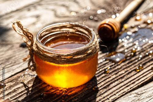 aromatic honey into jar on wooden table. bee products by organic natural ingredients concept, closeup
